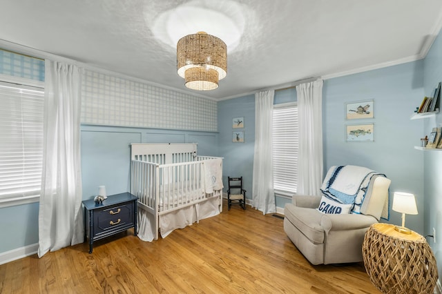 bedroom featuring light hardwood / wood-style flooring, a nursery area, and ornamental molding