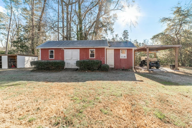 exterior space with a front lawn, a carport, and a storage unit