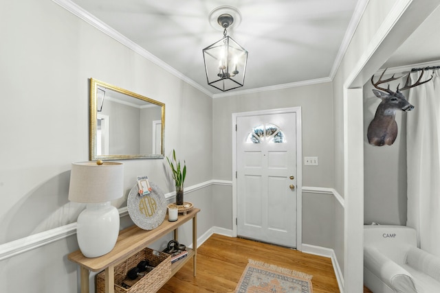 foyer entrance with hardwood / wood-style floors, ornamental molding, and a chandelier