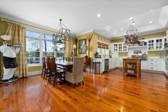 dining space featuring an inviting chandelier, crown molding, a raised ceiling, and wood-type flooring