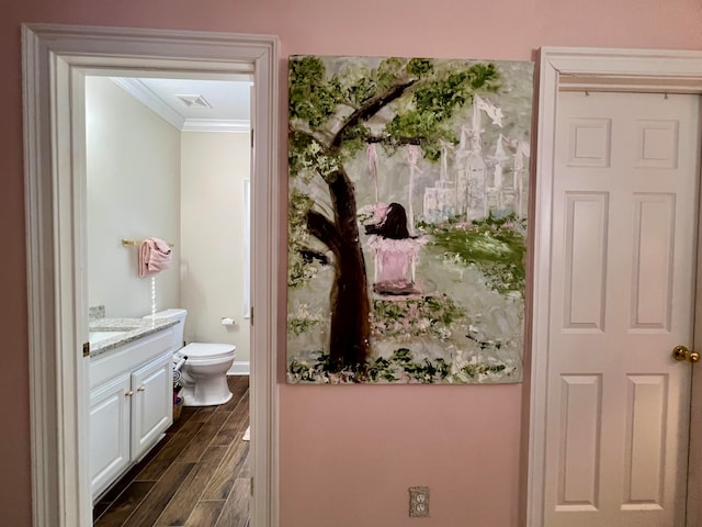 bathroom with hardwood / wood-style flooring, ornamental molding, toilet, and vanity