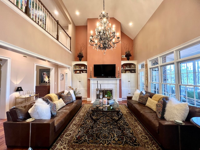 living room featuring an inviting chandelier, a brick fireplace, high vaulted ceiling, and hardwood / wood-style flooring