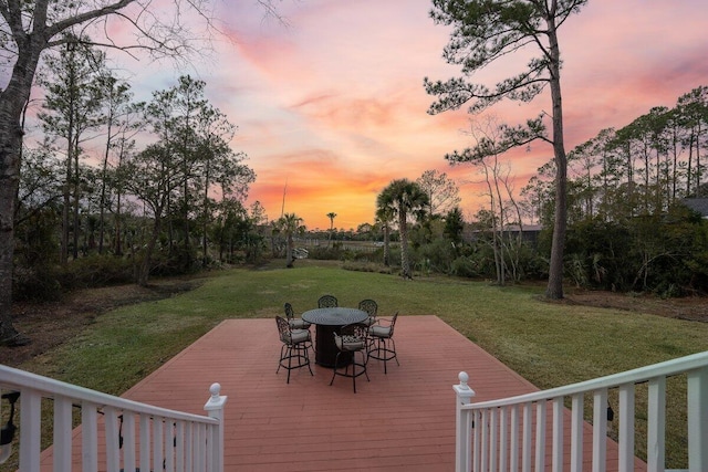 deck at dusk featuring a yard