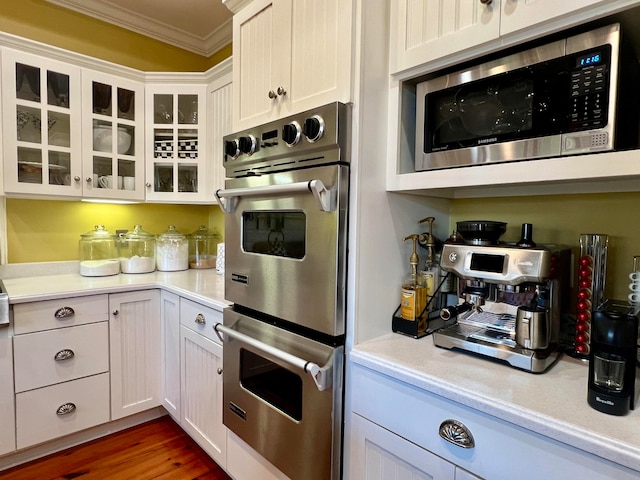 kitchen featuring ornamental molding, stainless steel appliances, white cabinets, and dark hardwood / wood-style flooring