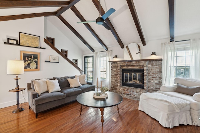 living area with a brick fireplace, beam ceiling, wood finished floors, high vaulted ceiling, and a ceiling fan