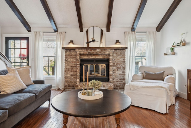 living room featuring beam ceiling, a brick fireplace, and hardwood / wood-style flooring