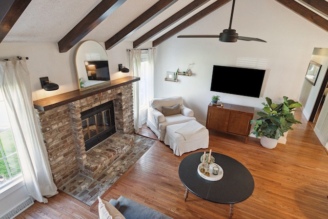 living room with wood finished floors, visible vents, lofted ceiling with beams, a fireplace, and ceiling fan