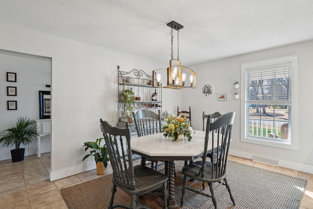 dining room featuring visible vents, a textured ceiling, an inviting chandelier, light tile patterned flooring, and baseboards