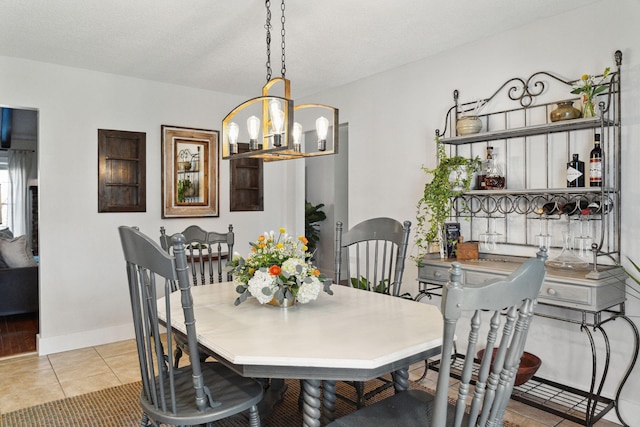 dining area featuring a chandelier, tile patterned floors, and baseboards