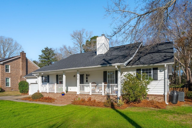 view of front of home with a front yard, a porch, an attached garage, central AC, and a chimney