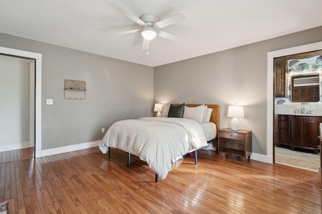 bedroom featuring a sink, baseboards, a ceiling fan, and light wood finished floors