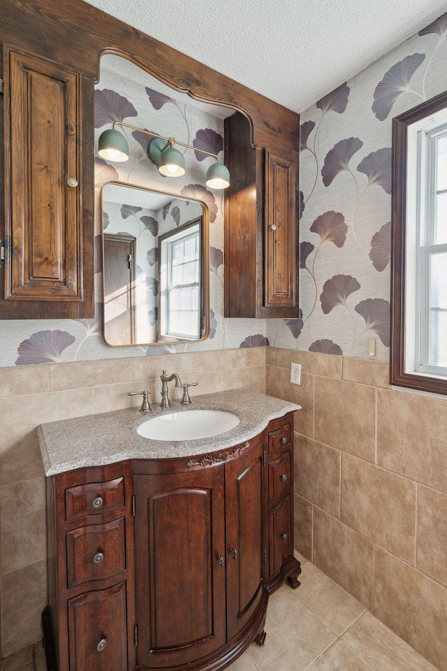 bathroom featuring vanity, a textured ceiling, wainscoting, tile walls, and tile patterned floors