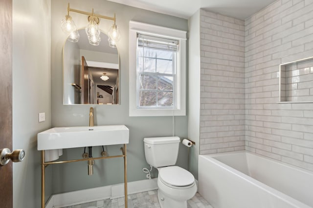 bathroom featuring toilet, baseboards, and a sink