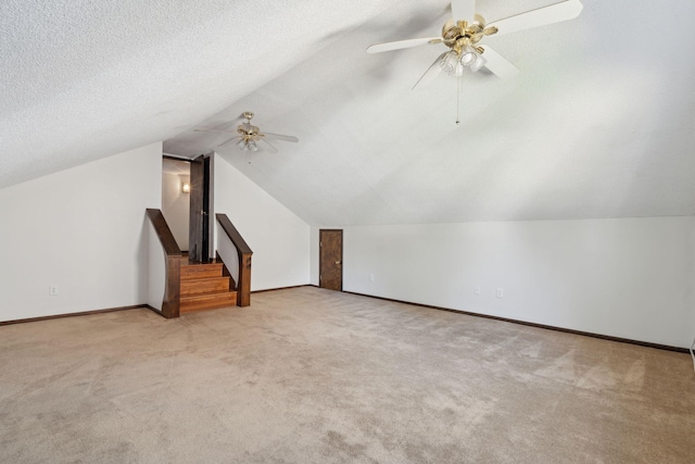 bonus room featuring baseboards, vaulted ceiling, carpet floors, a textured ceiling, and a ceiling fan