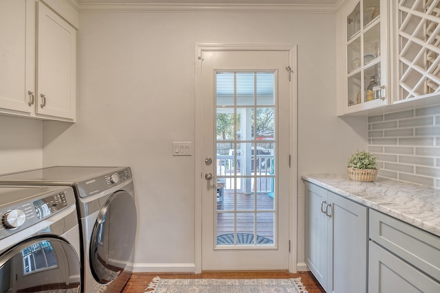 laundry area with cabinet space, baseboards, crown molding, and independent washer and dryer