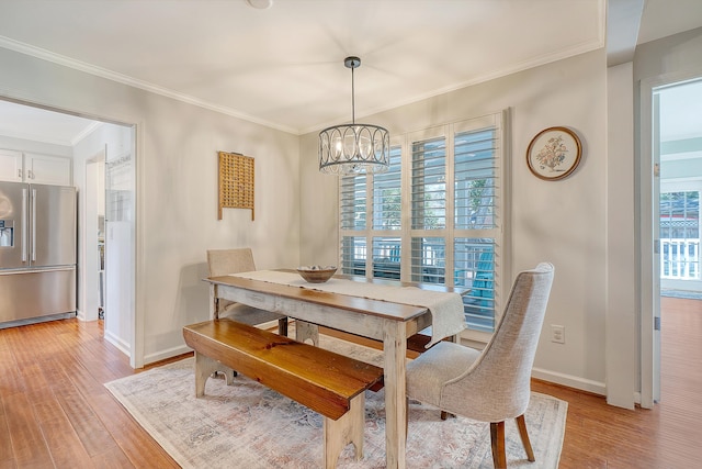 dining area with ornamental molding, light wood-type flooring, an inviting chandelier, and baseboards