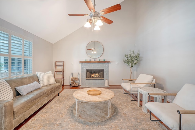 living room with high vaulted ceiling, wood finished floors, a ceiling fan, baseboards, and a tiled fireplace