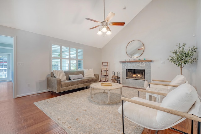 living area featuring visible vents, a ceiling fan, wood finished floors, high vaulted ceiling, and a tile fireplace