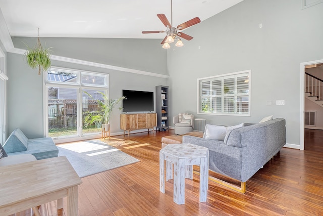 living room with visible vents, a ceiling fan, wood finished floors, stairs, and high vaulted ceiling