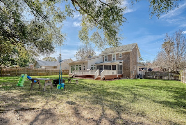 back of property with a lawn, central AC unit, a sunroom, a deck, and a fenced backyard