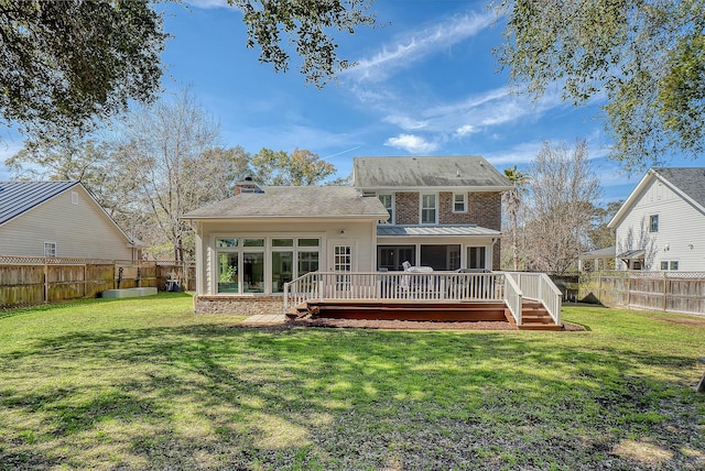 back of property with a sunroom, a fenced backyard, a deck, and a yard