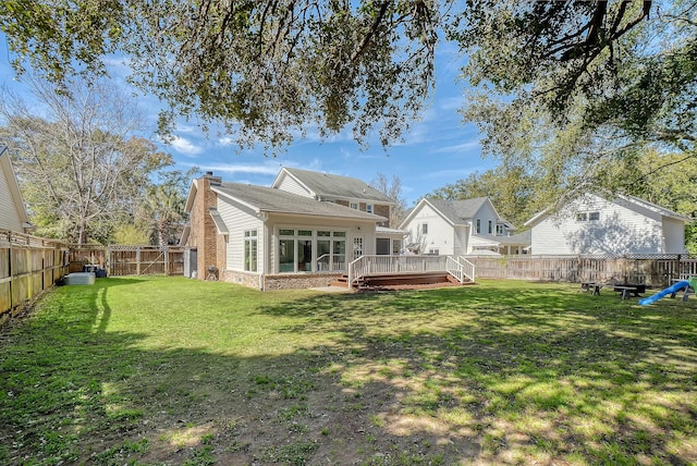 back of property with a lawn, a chimney, a fenced backyard, and a wooden deck