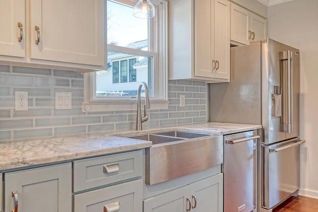 kitchen with stainless steel fridge, a sink, light stone countertops, and decorative backsplash