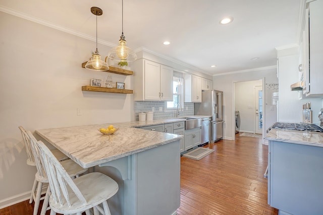 kitchen featuring hardwood / wood-style flooring, a peninsula, appliances with stainless steel finishes, open shelves, and tasteful backsplash