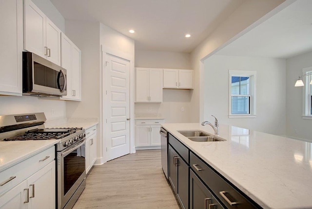 kitchen with sink, stainless steel appliances, white cabinetry, and light stone counters