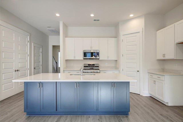 kitchen featuring white cabinets and a center island with sink