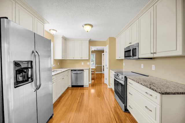 721 Lake Frances Dr, Charleston, SC 29412 - kitchen featuring appliances with stainless steel finishes, light wood finished floors, a textured ceiling, white cabinets, and stone counters