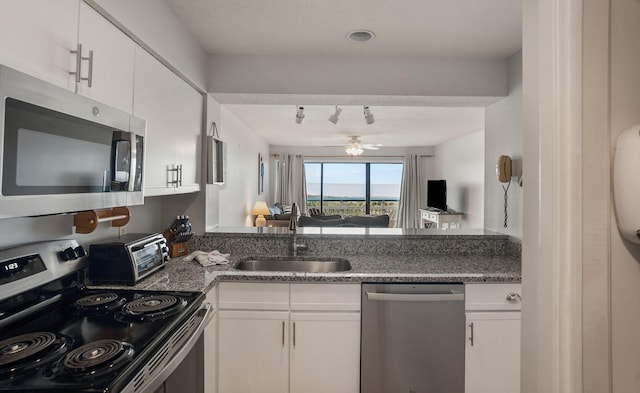 kitchen featuring appliances with stainless steel finishes, white cabinets, sink, and ceiling fan