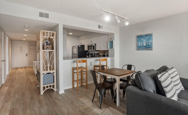 dining room featuring sink, light hardwood / wood-style flooring, and rail lighting