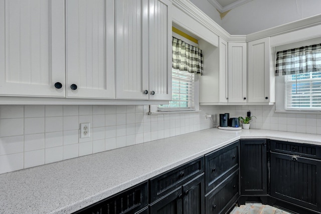 kitchen featuring white cabinetry, dark cabinetry, crown molding, and backsplash