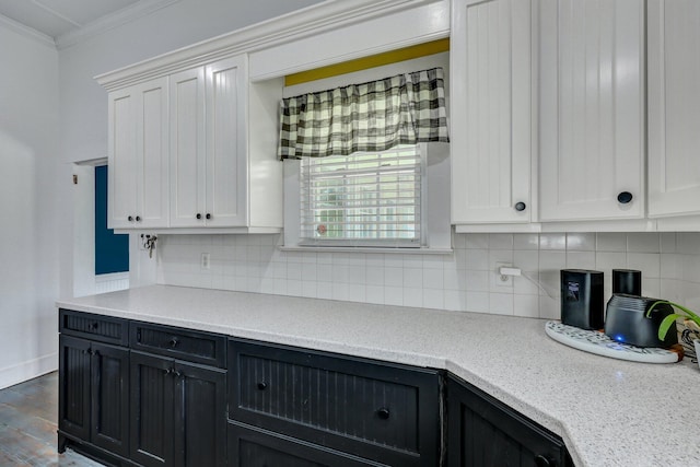 kitchen with tasteful backsplash, ornamental molding, white cabinets, and light countertops