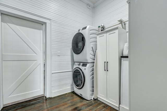 laundry room featuring cabinet space, dark wood-style flooring, and stacked washing maching and dryer