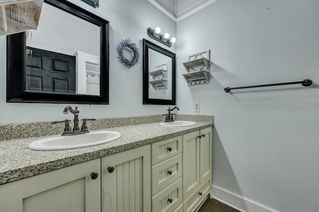 bathroom with double vanity, ornamental molding, baseboards, and a sink