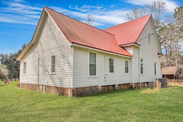 view of side of home with central air condition unit, a yard, and metal roof