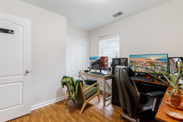 home office with baseboards, visible vents, and wood finished floors