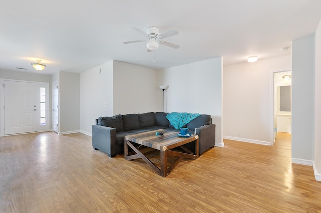 living area featuring baseboards, visible vents, ceiling fan, and light wood finished floors