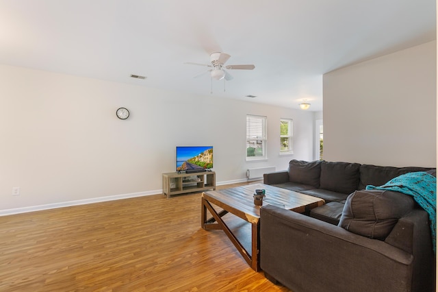 living room featuring baseboards, a ceiling fan, and light wood finished floors