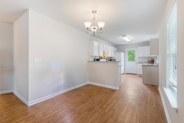 kitchen featuring white cabinets, an inviting chandelier, and wood finished floors