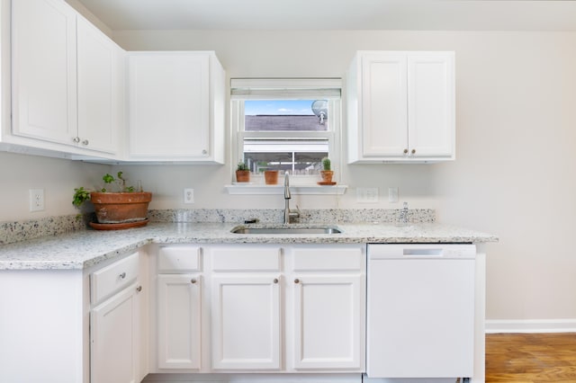 kitchen with white cabinets, white dishwasher, light stone counters, a sink, and wood finished floors