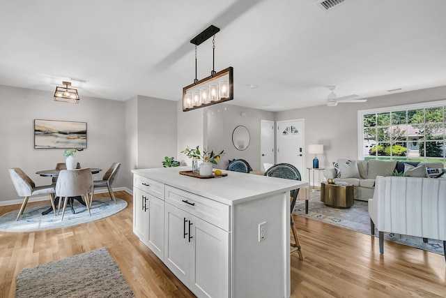 1391 Fairfield Ave, Charleston, SC 29407 - kitchen with light wood-type flooring, white cabinets, light countertops, a kitchen breakfast bar, and a kitchen island