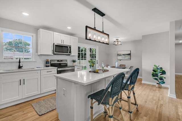 1391 Fairfield Ave, Charleston, SC 29407 - kitchen featuring stainless steel appliances, a sink, light countertops, white cabinetry, and a kitchen bar