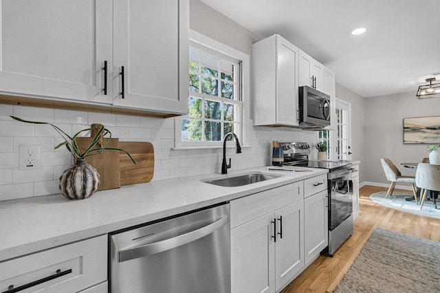 1391 Fairfield Ave, Charleston, SC 29407 - kitchen with stainless steel appliances, a sink, light wood-style flooring, white cabinetry, and tasteful backsplash