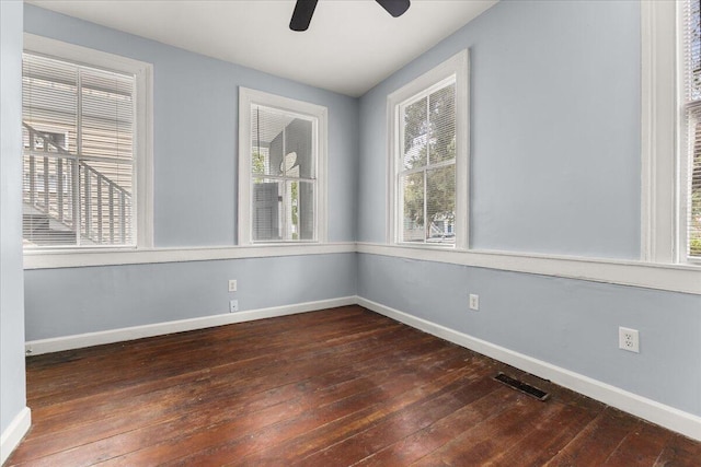 empty room with ceiling fan, dark hardwood / wood-style floors, and a healthy amount of sunlight