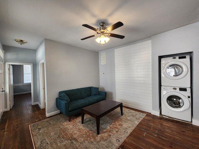 living room featuring stacked washer and dryer, dark hardwood / wood-style flooring, and ceiling fan