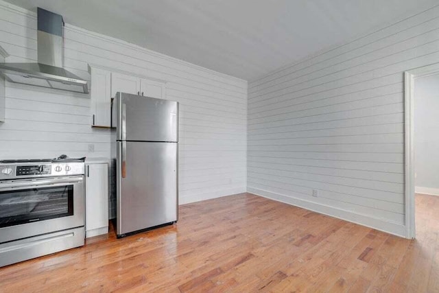 kitchen with stainless steel appliances, light hardwood / wood-style flooring, wall chimney exhaust hood, and white cabinetry