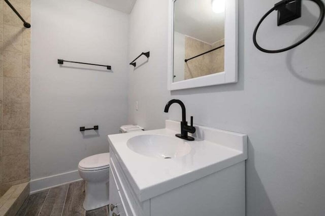 bathroom with vanity, a tile shower, and toilet